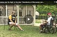 Two people, one in a wheelchair, sitting on front lawn talking.